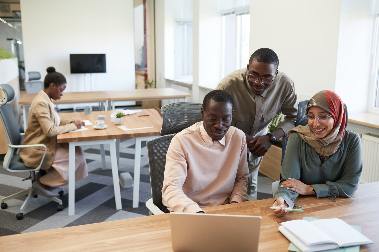A creative team working together around a laptop in a bright studio